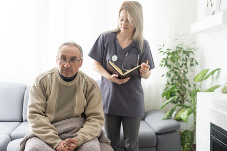 Caring nurse talks to old patient holds his hand sit in living room at homecare visit provide psychological support listen complains showing empathy encouraging. Geriatrics medicine caregiving conceptの写真素材