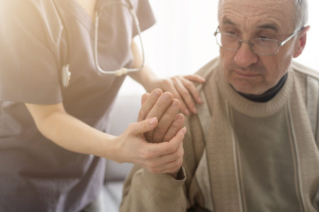 Caring nurse talks to old patient holds his hand sit in living room at homecare visit provide psychological support listen complains showing empathy encouraging. Geriatrics medicine caregiving conceptの写真素材