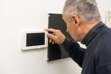 an elderly man repairs an intercom.