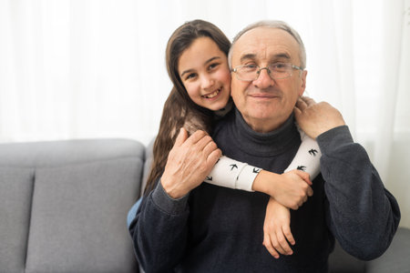 Family time. Pretty granddaughter hugging with her grandfather.