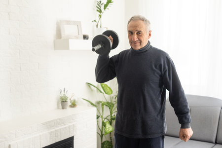 Developing muscles. Strong fit aged man while training with dumbbellsの写真素材