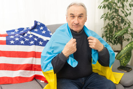 Senior man with Ukrainian flag. Ukraine national flag colors. Pray for Ukraine, stop the war, save Ukraine people and children. No invasion, occupation and terrorism. and usa flag.の写真素材