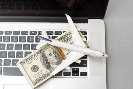 plane, money and keyboard. online purchase of airline tickets on a gray wooden tableの写真素材