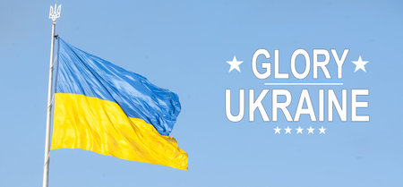 slogan Glory to Ukraine in Ukrainian on waved national flagの写真素材