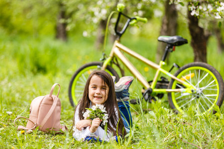 Portrait of a smiling little girl lying on green grassの写真素材