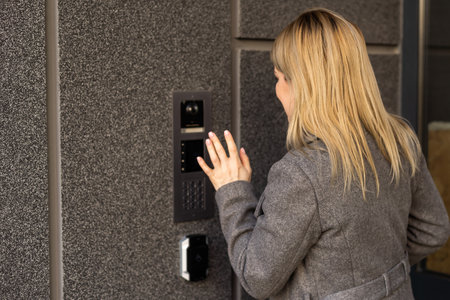 Middle aged woman pushing button of intercomの写真素材