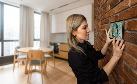 pretty blonde woman using smart home control panel.の写真素材