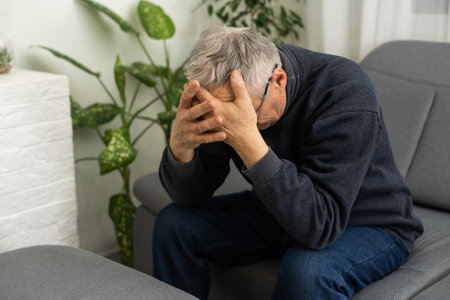 Tired old man suffering from headache, massaging his temples. Strong migraine attack. An elderly man has a headache, massaging his templesの写真素材