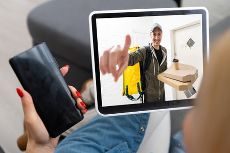 Delivery man ringing door bell on cctv secure camera system on tablet appの写真素材