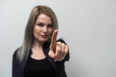 Studio shot of a young blond woman pointing towards you