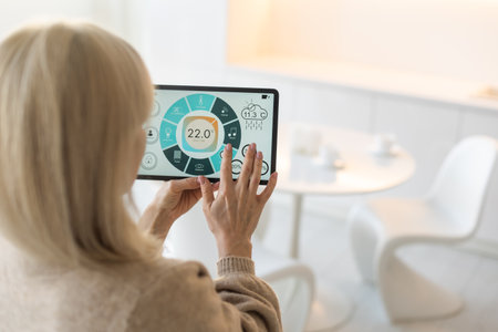 Woman controlling smart home devices using a digital tablet with launched application in the white living room. Smart home conceptの写真素材