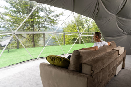 a man is soldering in the transparent dome of the glamping hotelの写真素材
