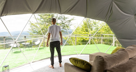 a man is soldering in the transparent dome of the glamping hotelの写真素材
