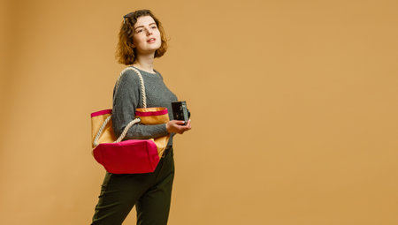 Portrait of a smiling young woman in summer hat standing w at copy space isolated over beige backgroundの写真素材