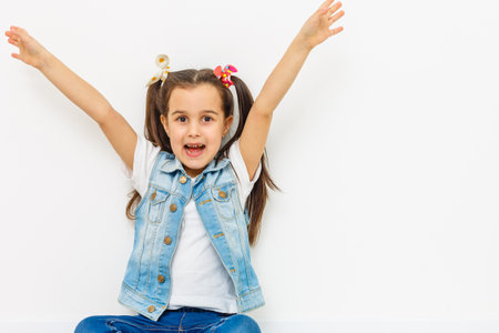 happy little girl with hands raised on white backgroundの写真素材
