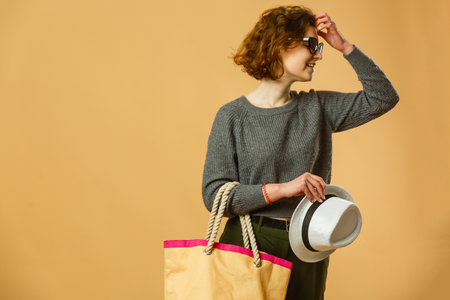 Travel and Lifestyle concept: Full length studio portrait of pretty young student woman holding passport with tickets. Isolated on bright yellow backgroundの写真素材