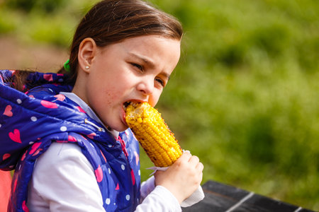 Girl eating corn in a fieldの写真素材