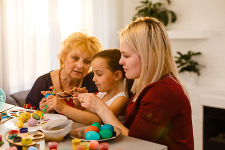Little girl and her grandmother painting Easter eggs at home.の写真素材