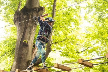 adventure climbing high wire park - children on course rope park. Portrait of cute little girl walk...