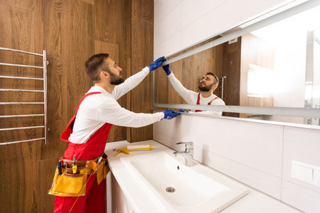 Man installing a mirror on wall in his renewed bathroomの写真素材