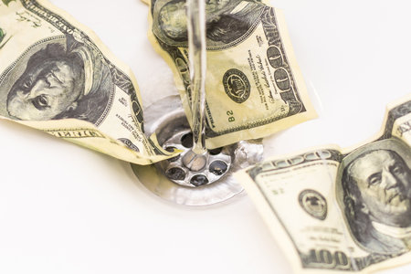 Cash Money Going Down Sink Drain Isolated on White Backgroundの写真素材