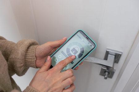 Woman hands using phone scan to digital door lock security systems at homeの写真素材