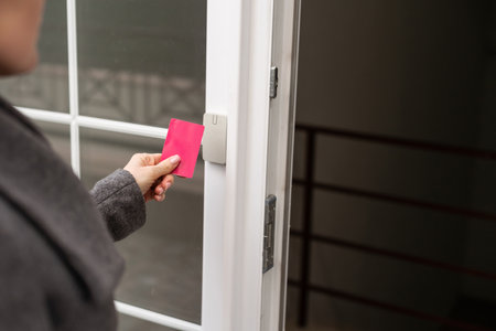 Woman attaches card to the electronic reader to access the apartment. Card entry, personal identification, keyless access, technologies in everyday life.の写真素材