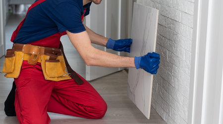 Master is wearing work clothes, is checking horizon of installing tiles, using building level,...