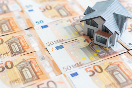 Buying and building a house.House and money. Real estate market. house with gray roof on euro banknotes background.の写真素材
