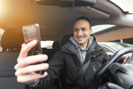 Success in motion. Handsome young man in full suit smiling while driving a carの写真素材
