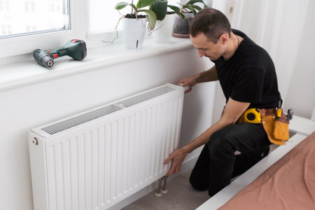 The process of installing a battery to water pipes. Heating system. Nearby standing masterの写真素材