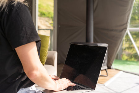 Joyful blonde girl smiling and talking via video call on laptop, home office, working remotely, explaining a strategy, freelancer, discussing a new project with team.の写真素材