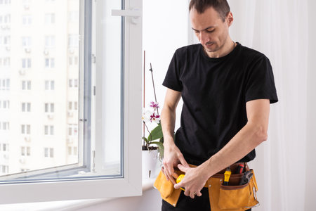 Young repairman fixing window frame in room at daytimeの写真素材