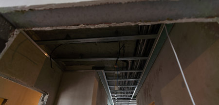 Construction worker assemble a suspended ceiling with drywall and fixing the drywall to the ceiling metal frame with screwdriver. Renovation, construction and do it yourselfの写真素材