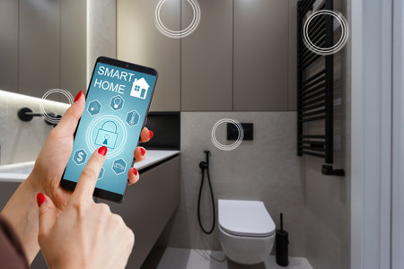 Internet of things. Focus on modern smartphone with blank mockup screen for smart home control system interface in young female customer user hand. Blurred living room interior on background. Close upの写真素材