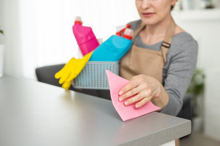 Woman cleaning and polishing the kitchen worktop with a spray detergent, housekeeping and hygiene concept.の写真素材