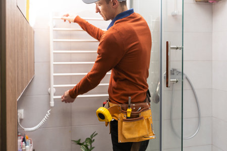young foreman measuring shower cabin in modern bathroom.の写真素材