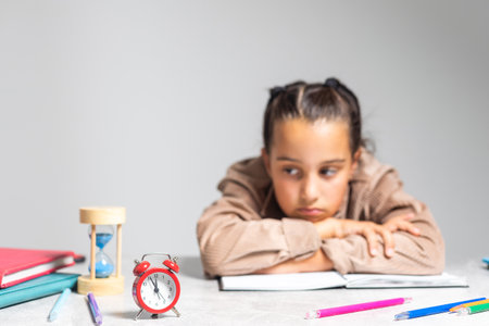 Pretty little girl tired of doing homework at table.の写真素材