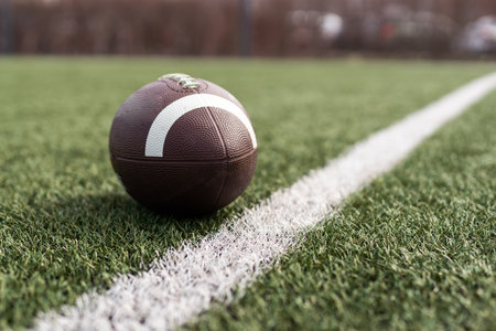 American football ball on green grass field background.の写真素材