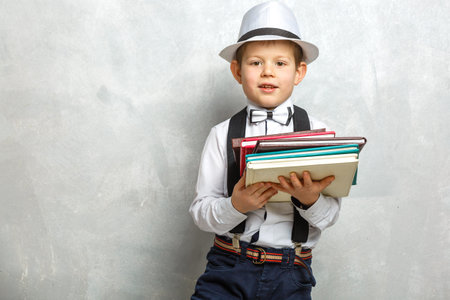 Elementary school student carrying notebooks over a gray background