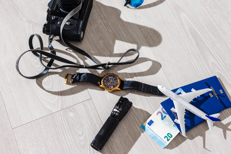 Travel preparation. A lot of objects are scattered on gray background - a camera, tickets,...
