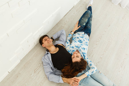 Dreamy couple lying on floor in empty room and looking up, imagine future interior design project, white background.の写真素材
