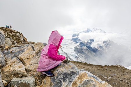 Children hiking in Alps mountains. Kids look at mountain in Austria. Spring family vacation. Outdoor...
