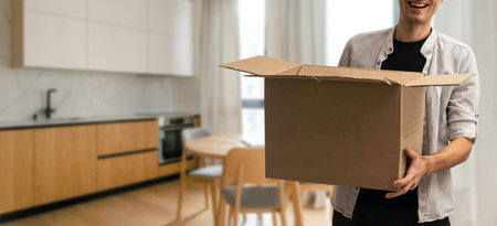 enthusiastic young man carrying cardboard box, moving out of home