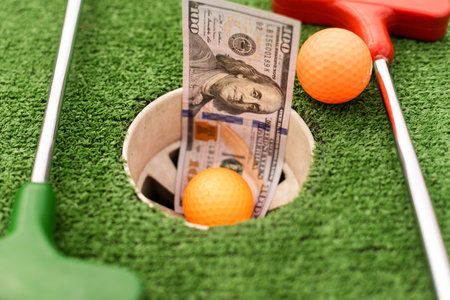 Money, mini golf balls on grass. Concept of sports betの写真素材