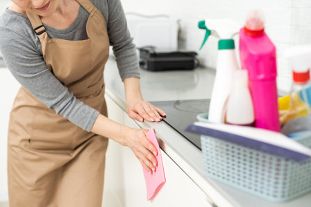 Weekend homework. Young pretty woman cleans in cozy living room at home. A beautiful woman in home clothes and rubber gloves in a bright room.の写真素材