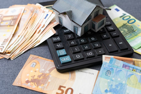 Miniature model of houses on stacked euro banknotes, on isolated white background. Real estate investment concept. Saving money for future retirement.の写真素材