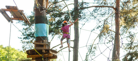 male instructor helps the child on the rope road in the training camp.