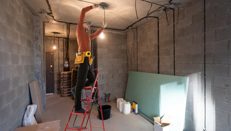 Electrician repairing ceiling fan with lamps indoors. Space for text.の写真素材