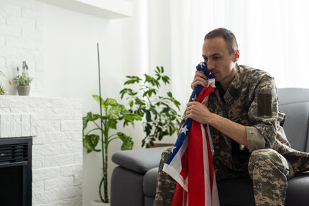 upset American soldier holding flag of United States while crying during memorial day